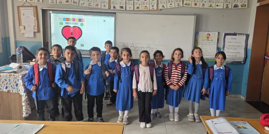 Eleven students at a school in Kars, Türkiye, stand together in their classroom, several wearing their new backpacks provided through BTF's Back to School Campaign.