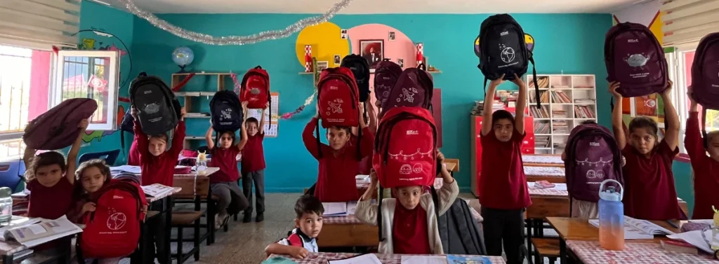 Students at Haydarlar Elementary School in Hatay, Türkiye, hold up colorful BTF backpacks provided through the 2026 Back to School Campaign.