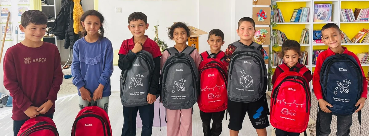 Eight students at Yastıca Elementary School in Kilis, Türkiye, stand together holding red and navy BTF backpacks provided through the 2026 Back to School Campaign.