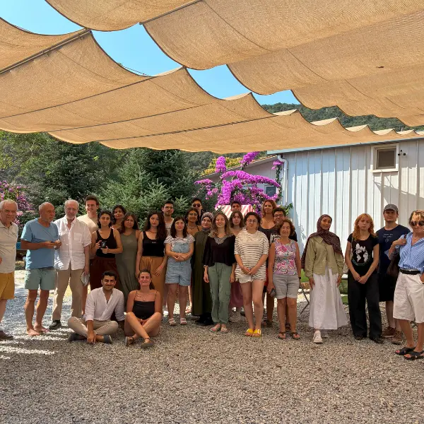 Group of participants and organizers at the 2025 Nâzım Hikmet Summer Camp pose together outdoors beneath a large shade canopy in Büyükada, Istanbul.
