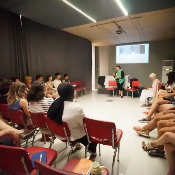 A speaker leads an indoor discussion with participants seated in a circle during the 2025 Nâzım Hikmet Summer Camp in Büyükada, Istanbul.