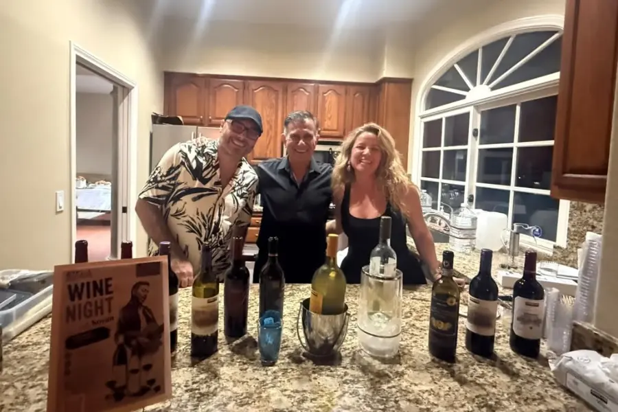 Three attendees smile behind a table displaying wine bottles at Bridge to Türkiye Fund’s San Diego Giving Circle Third Wine Night.